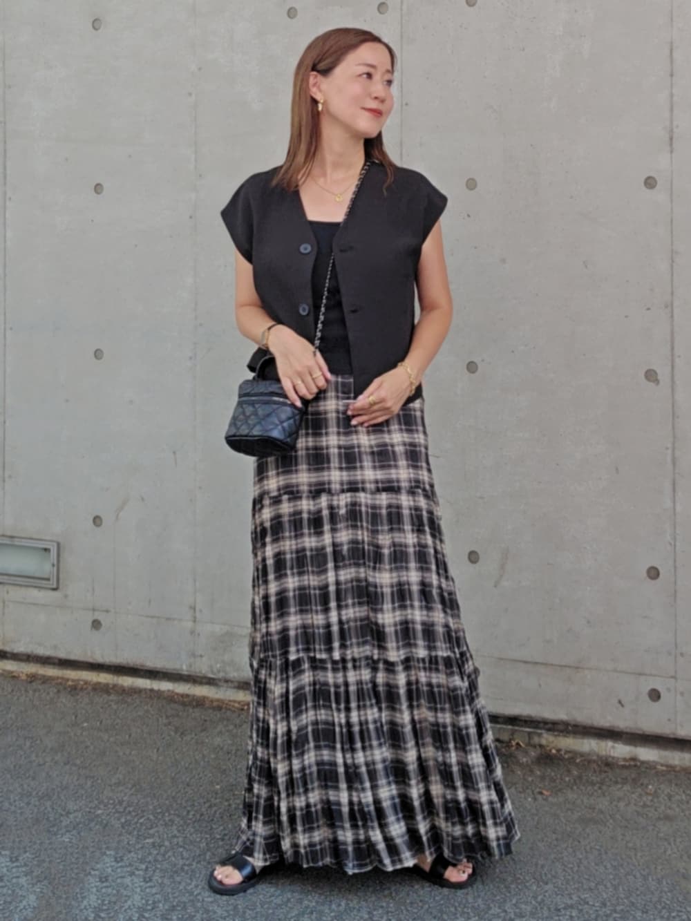 ブラック系のベスト、ブラック系のスカート、ブラック系のバッグを着用したレディースの夏コーディネートの2枚目の写真