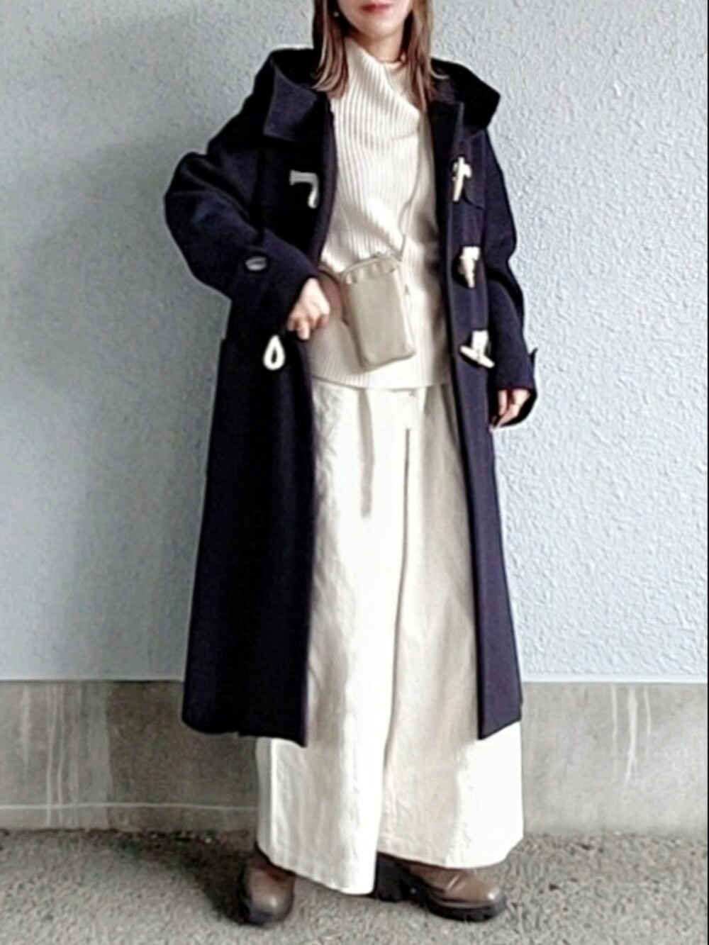 ブラック系のダッフルコート、ホワイト系のその他パンツ、ベージュ系のブーツを着用したレディースの冬コーディネートの2枚目の写真