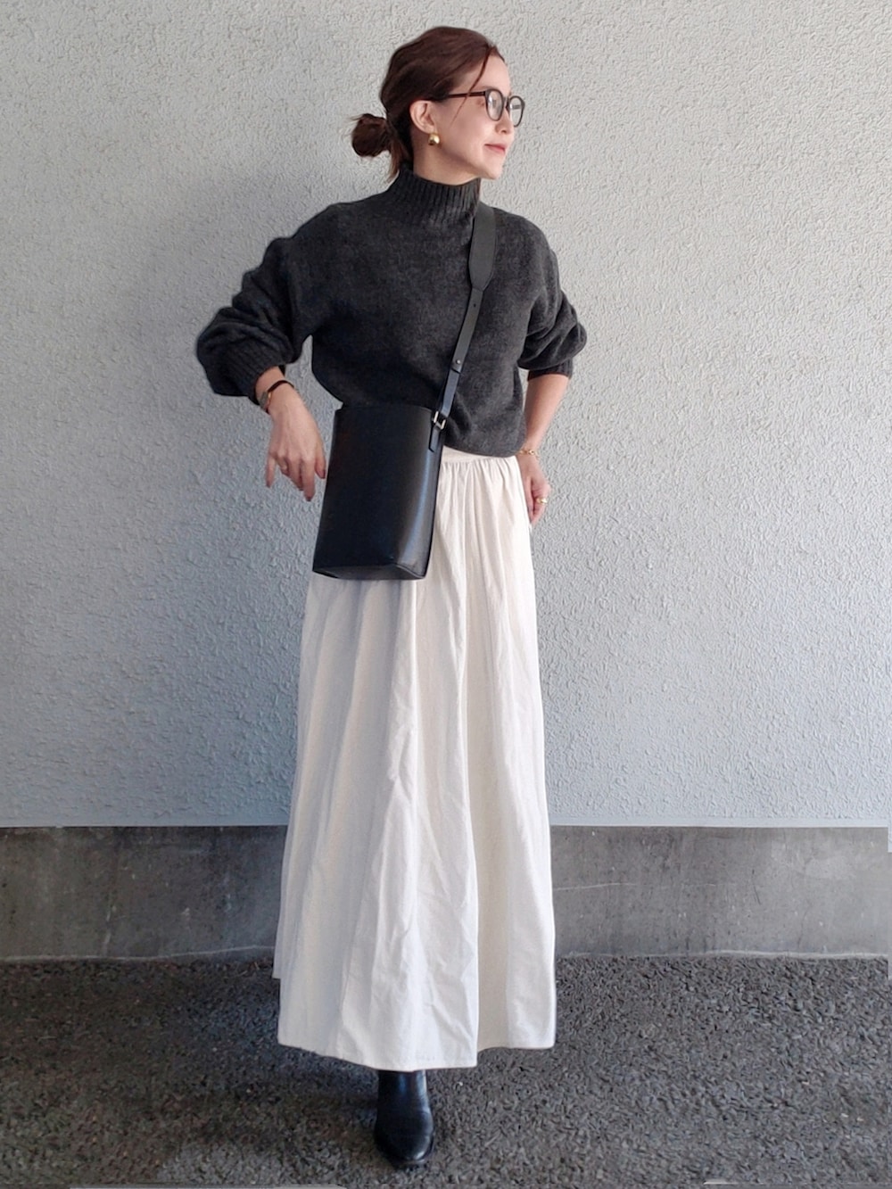 グレー系のニット/セーター、ブラック系のバッグ、ブラック系のブーツを着用したレディースの冬コーディネートの2枚目の写真