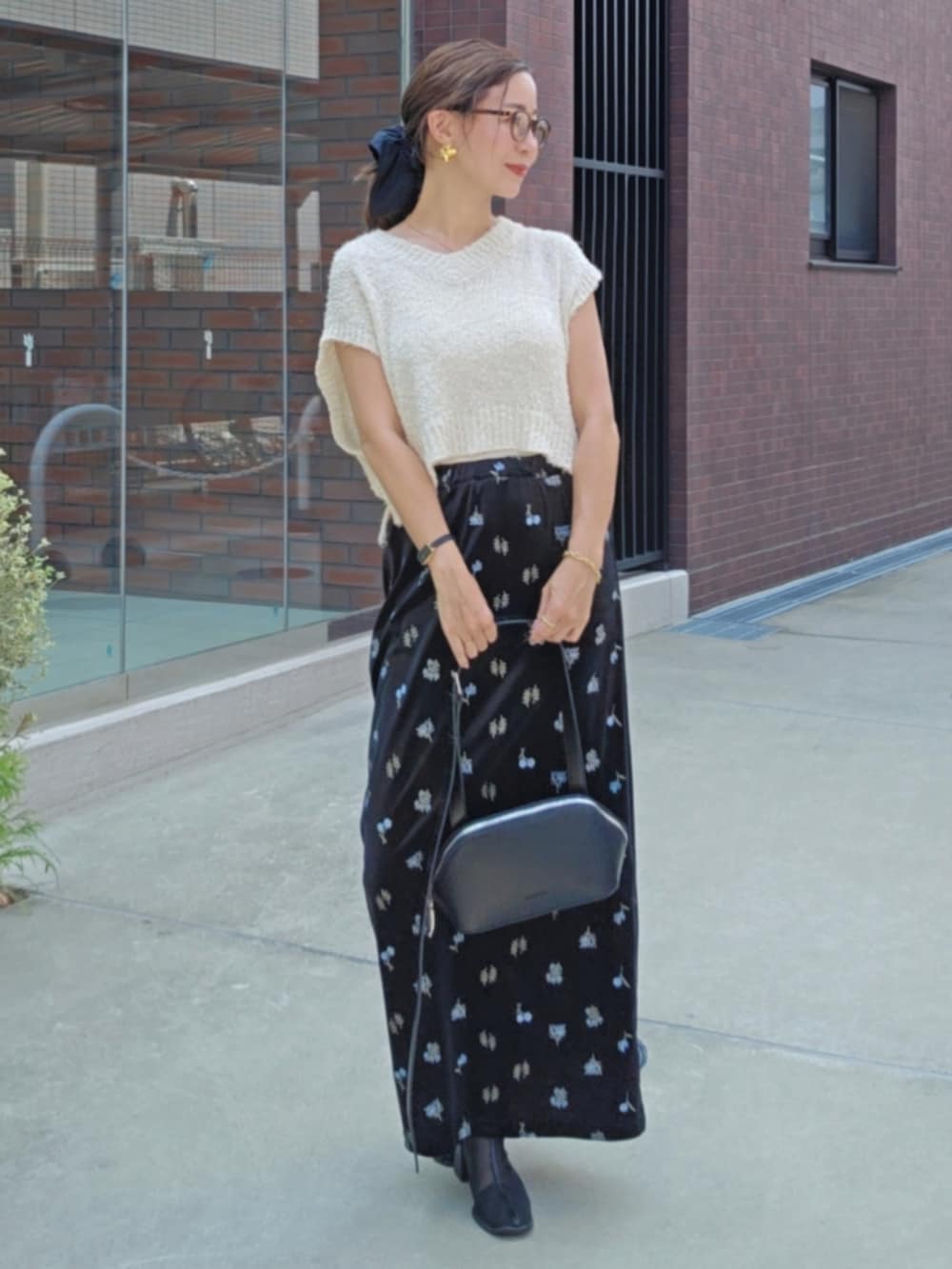 ブラック系のスカート、ホワイト系のトップス、ブラック系のブーツを着用したレディースの夏コーディネートの2枚目の写真