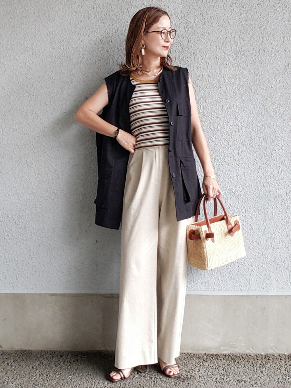 ベージュ系のその他パンツ、ブラウン系のサンダル、ブラック系のベストを着用したレディースの春コーディネートの2枚目の写真