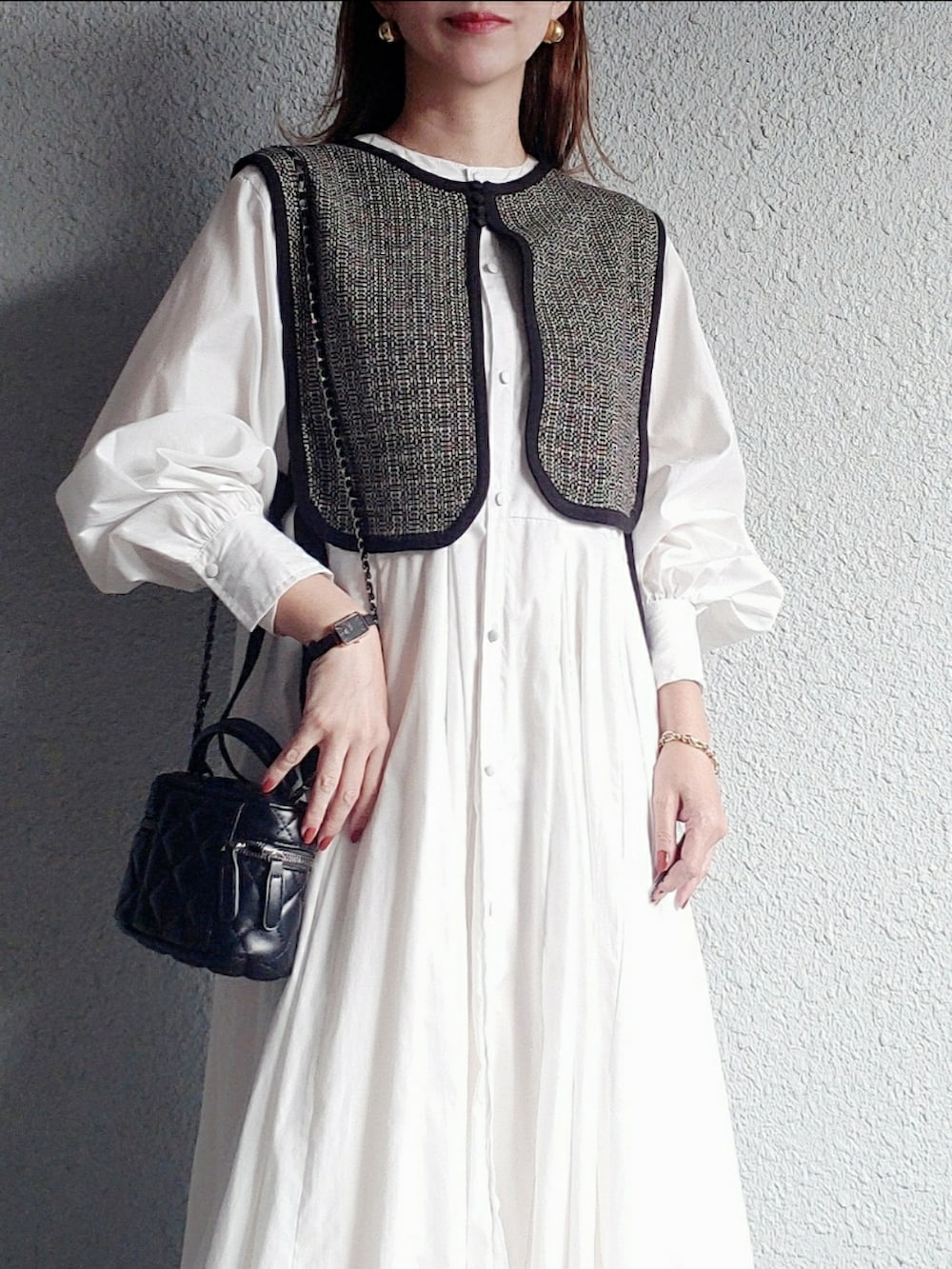 ブラック系のベスト、ブラック系のブーツ、ブラック系のバッグを着用したレディースの秋コーディネートの3枚目の写真