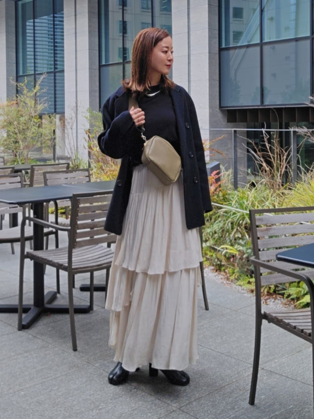 ブラック系のTシャツ/カットソー、ホワイト系のスカート、ブラック系のブーツを着用したレディースの春コーディネートの3枚目の写真