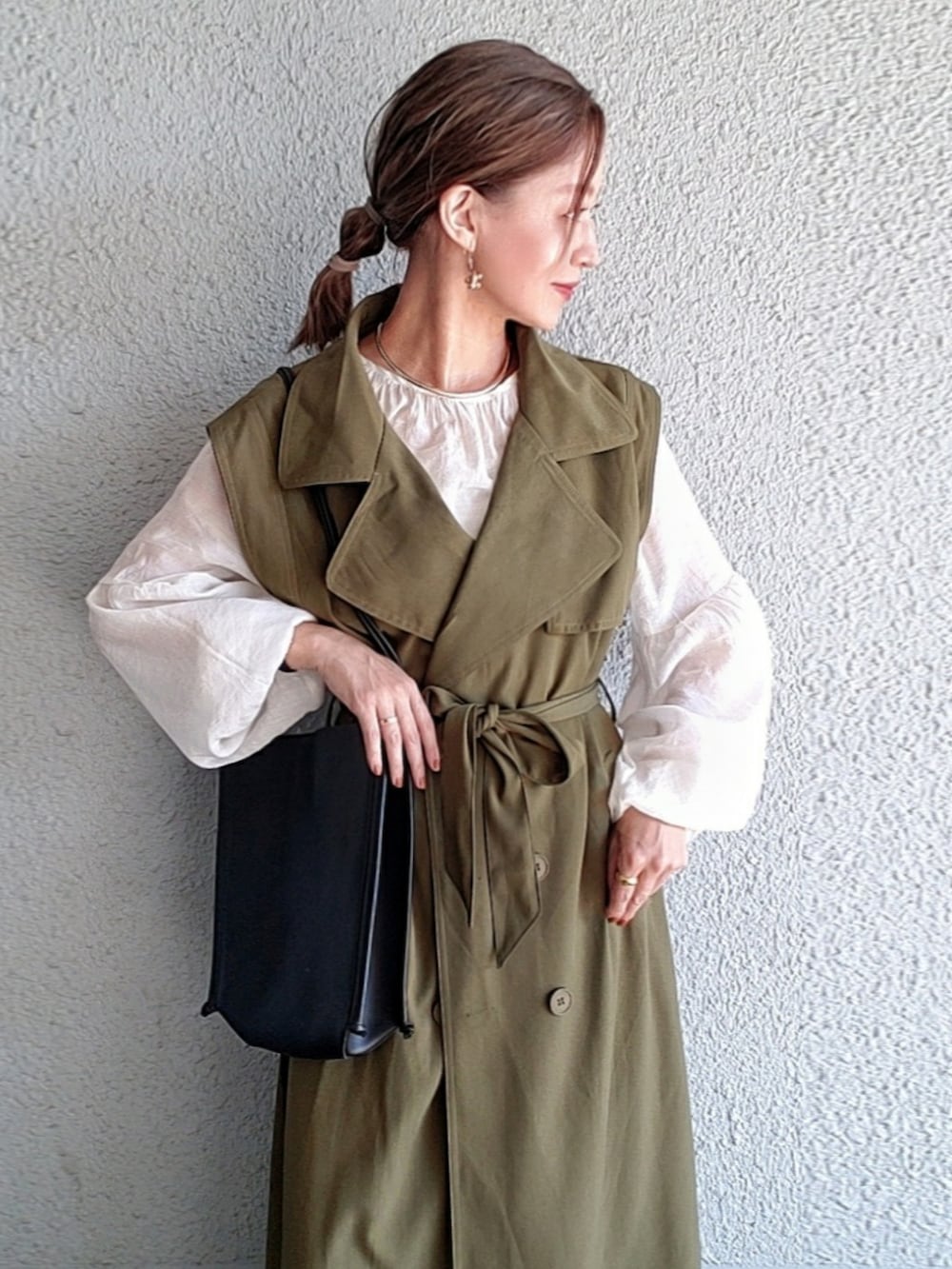 ブラック系のトートバッグ、ブラック系のブーツ、グリーン系のトレンチコートを着用したレディースの秋コーディネートの3枚目の写真