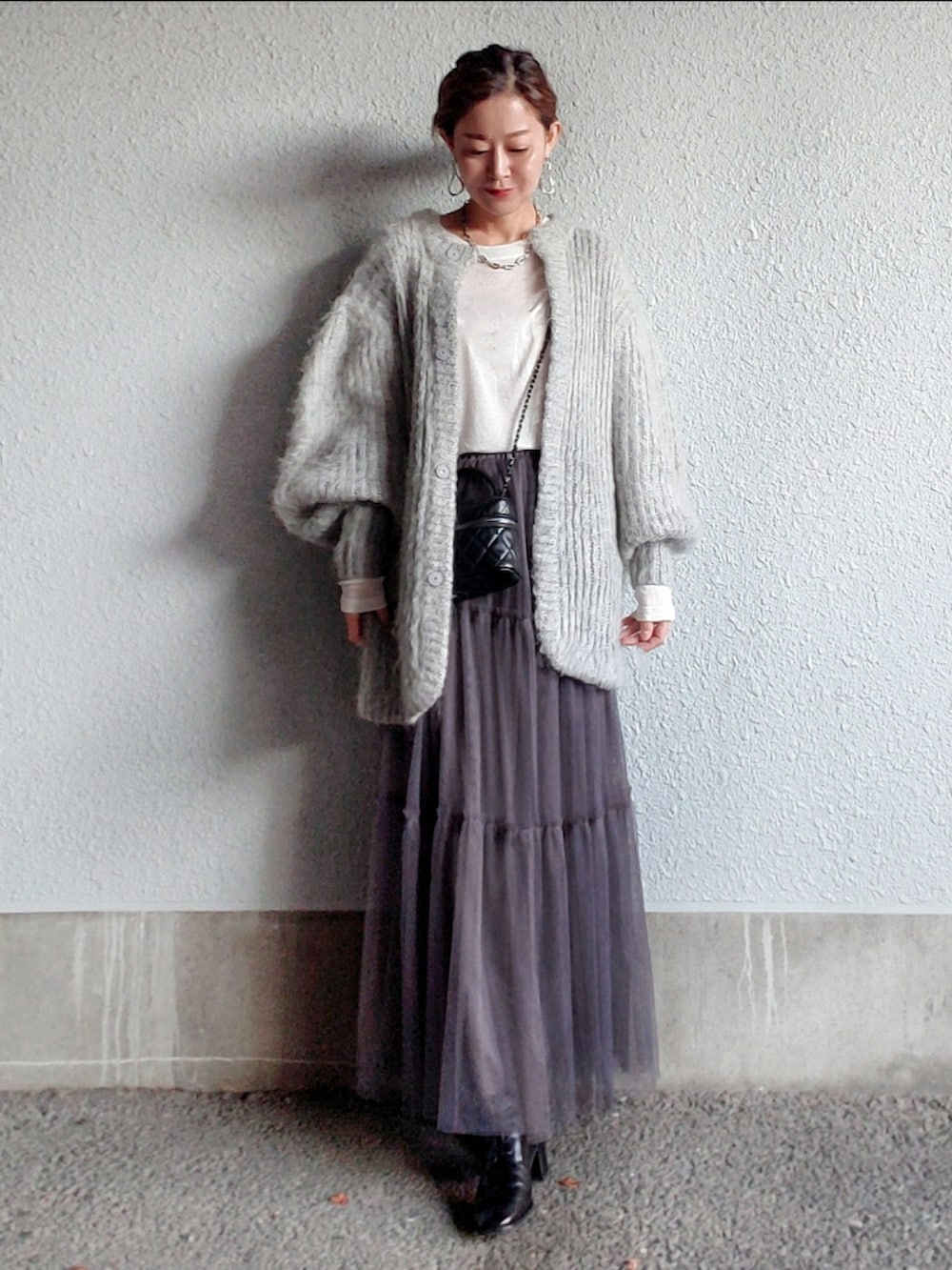 グレー系のスカート、ブラック系のブーツ、ホワイト系のTシャツ/カットソーを着用したレディースの秋コーディネートの3枚目の写真