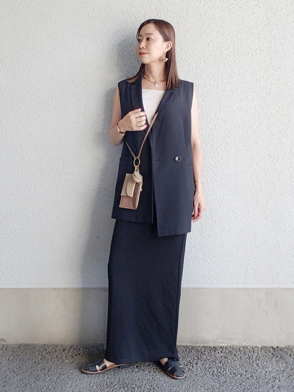 ブルー系のベスト、ブラック系のワンピース、ブラウン系のショルダーバッグを着用したレディースの夏コーディネートの3枚目の写真