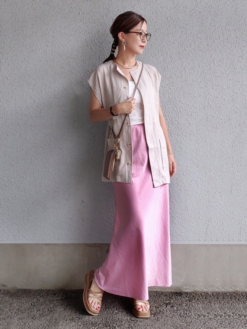 ピンク系のスカート、グレー系のベスト、ブラウン系のサンダルを着用したレディースの夏コーディネートの2枚目の写真