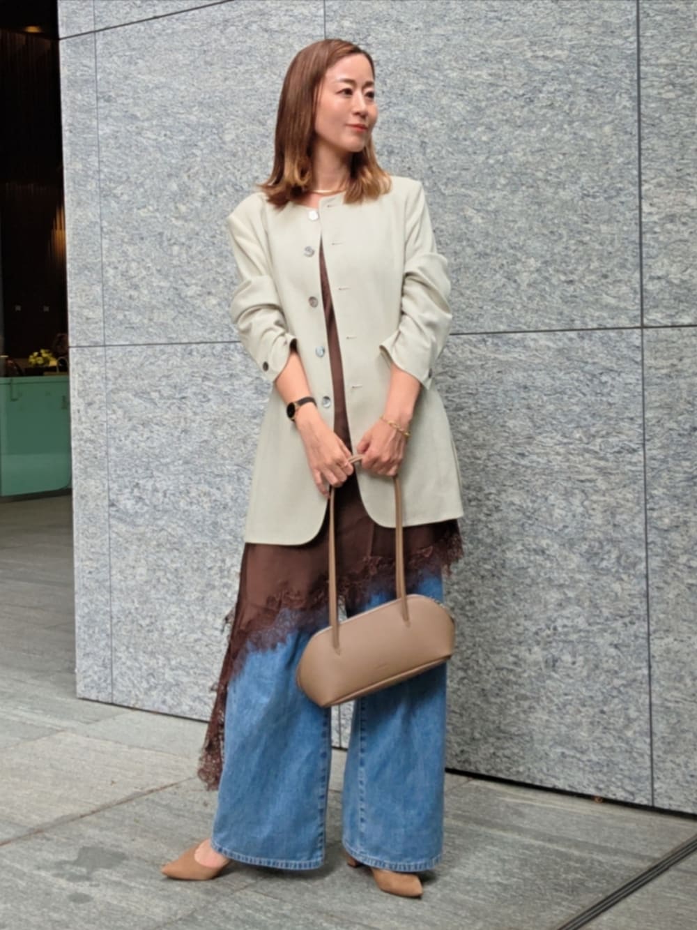 ベージュ系のパンプス、ブルー系のデニムパンツ、ブラウン系のショルダーバッグを着用したレディースの春コーディネートの3枚目の写真