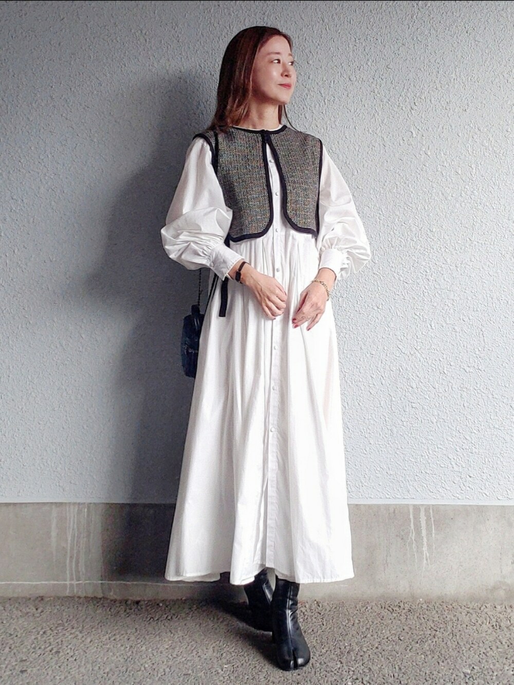 ブラック系のベスト、ブラック系のブーツ、ブラック系のバッグを着用したレディースの秋コーディネートの4枚目の写真