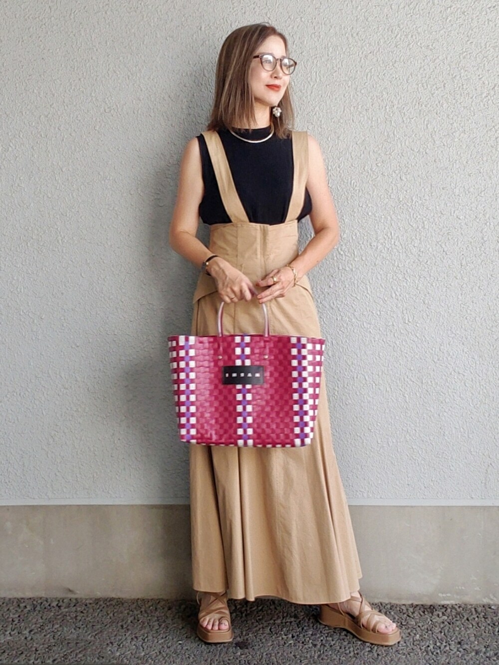 ベージュ系のスカート、ブラック系のタンクトップ、レッド系のかごバッグを着用したレディースの夏コーディネートの2枚目の写真