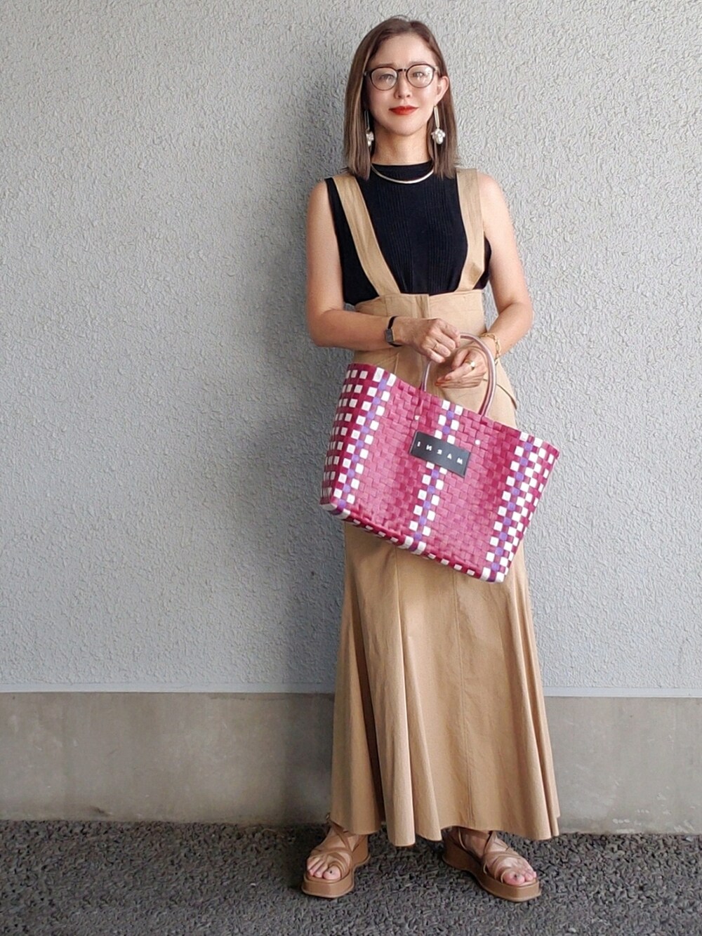 ベージュ系のスカート、ブラック系のタンクトップ、レッド系のかごバッグを着用したレディースの夏コーディネートの3枚目の写真