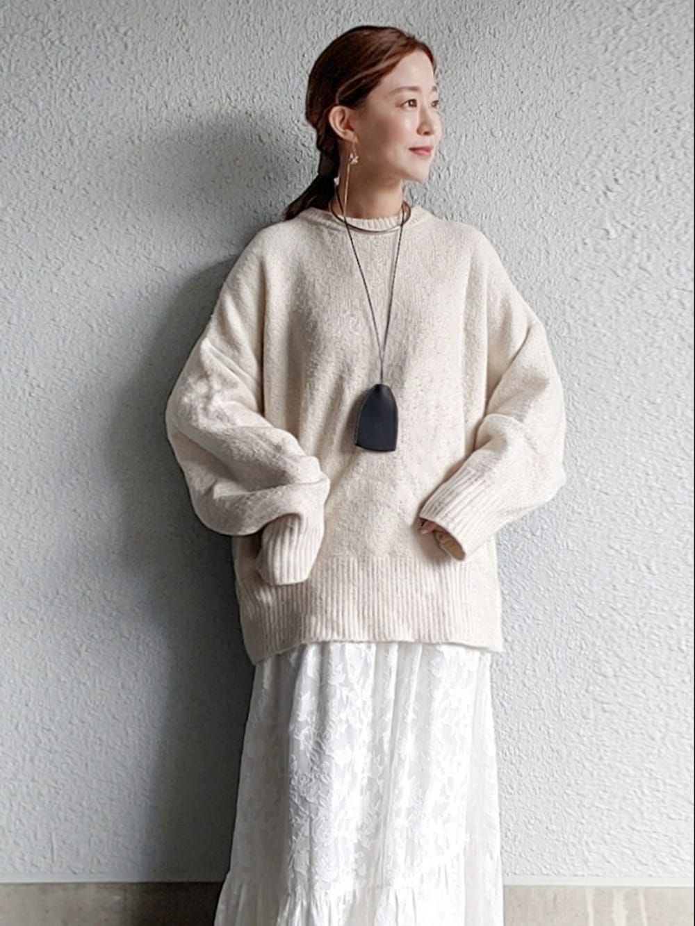 ホワイト系のニット/セーター、ホワイト系のスカート、グレー系のサンダルを着用したレディースの冬コーディネートの5枚目の写真