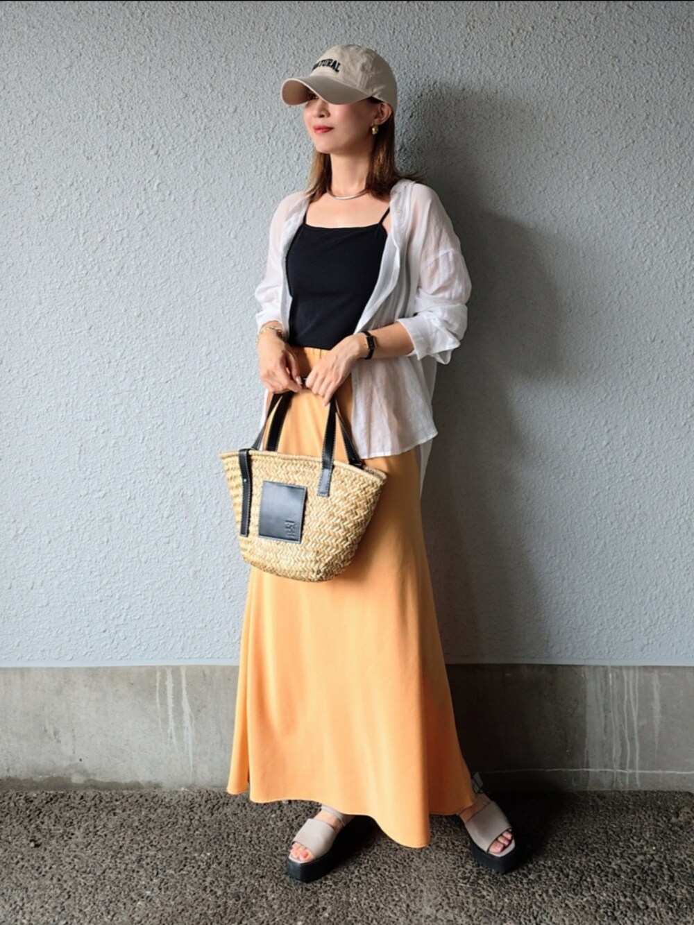 ブラック系のキャミソール、オレンジ系のスカート、ブラック系のかごバッグを着用したレディースの夏コーディネートの3枚目の写真