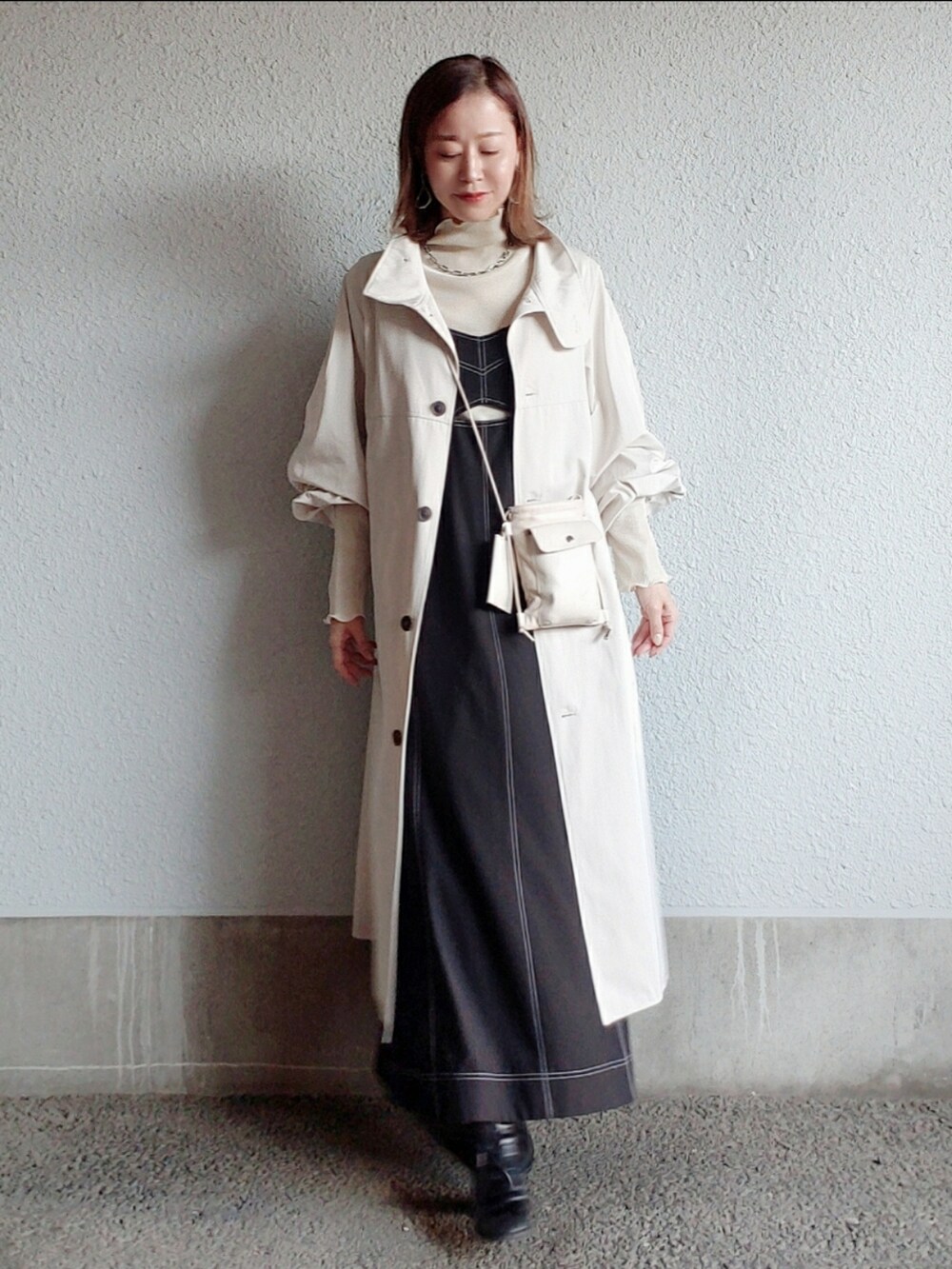 ホワイト系のトレンチコート、ブラック系のワンピース/ドレス、ブラック系のブーツを着用したレディースの春コーディネートの3枚目の写真
