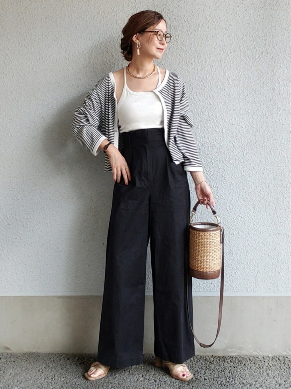 ホワイト系のキャミソール、ブラック系のチノパンツ、ブラウン系のサンダルを着用したレディースの春コーディネートの2枚目の写真