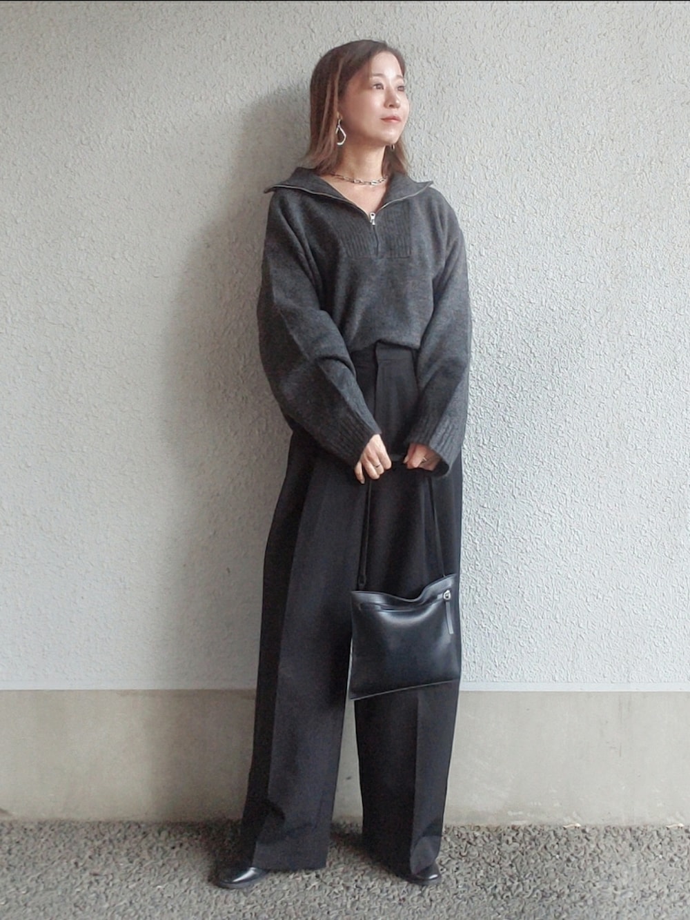 ブラック系のスラックス、ブラック系のブーツ、シルバー系のピアス（両耳用）を着用したレディースの冬コーディネートの4枚目の写真