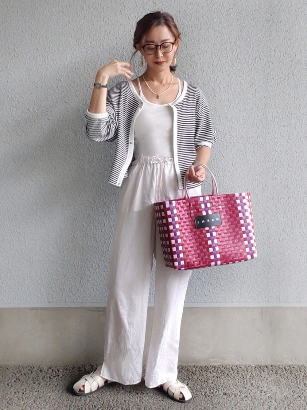 レッド系のかごバッグ、ホワイト系のその他パンツ、ホワイト系のサンダルを着用したレディースの春コーディネートの2枚目の写真