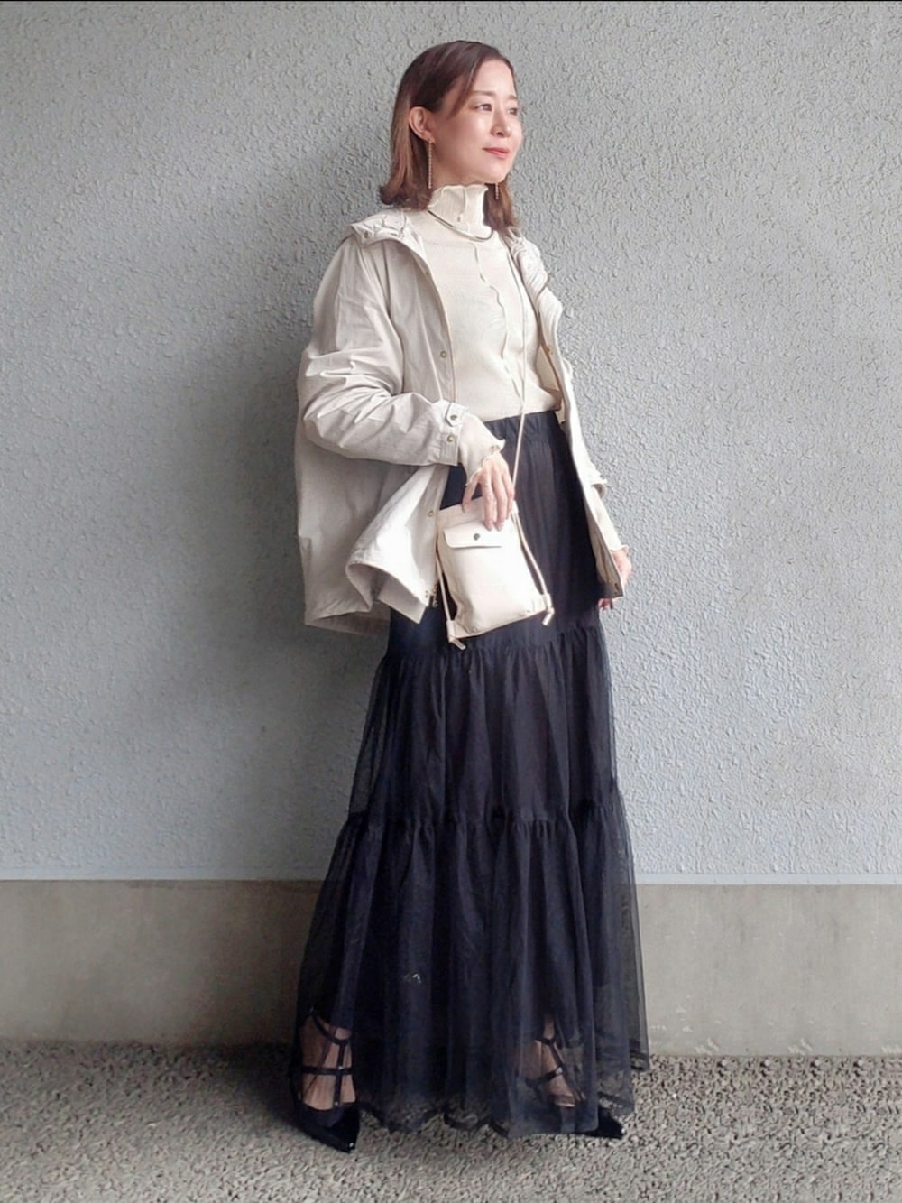 ホワイト系のマウンテンパーカー、ホワイト系のTシャツ/カットソー、ブラック系のスカートを着用したレディースの春コーディネートの3枚目の写真