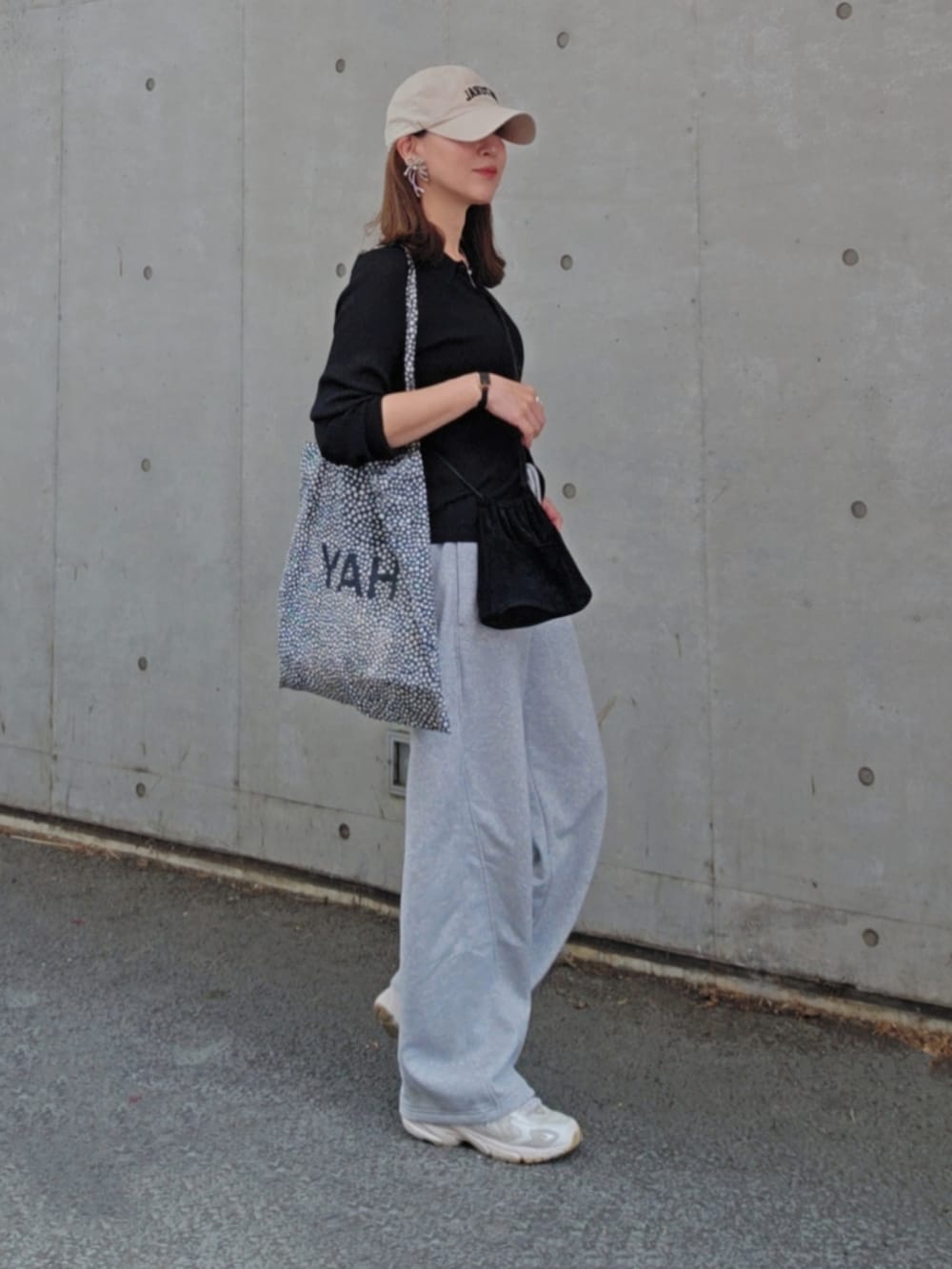 グレー系のパンツ、ベージュ系のスニーカー、ブラック系のトップスを着用したレディースの春コーディネートの3枚目の写真