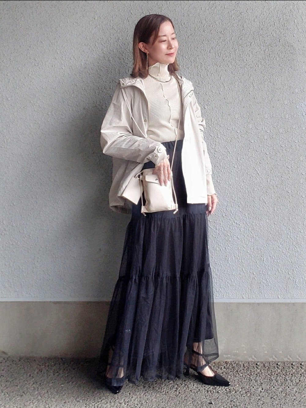 ホワイト系のマウンテンパーカー、ホワイト系のTシャツ/カットソー、ブラック系のスカートを着用したレディースの春コーディネートの2枚目の写真