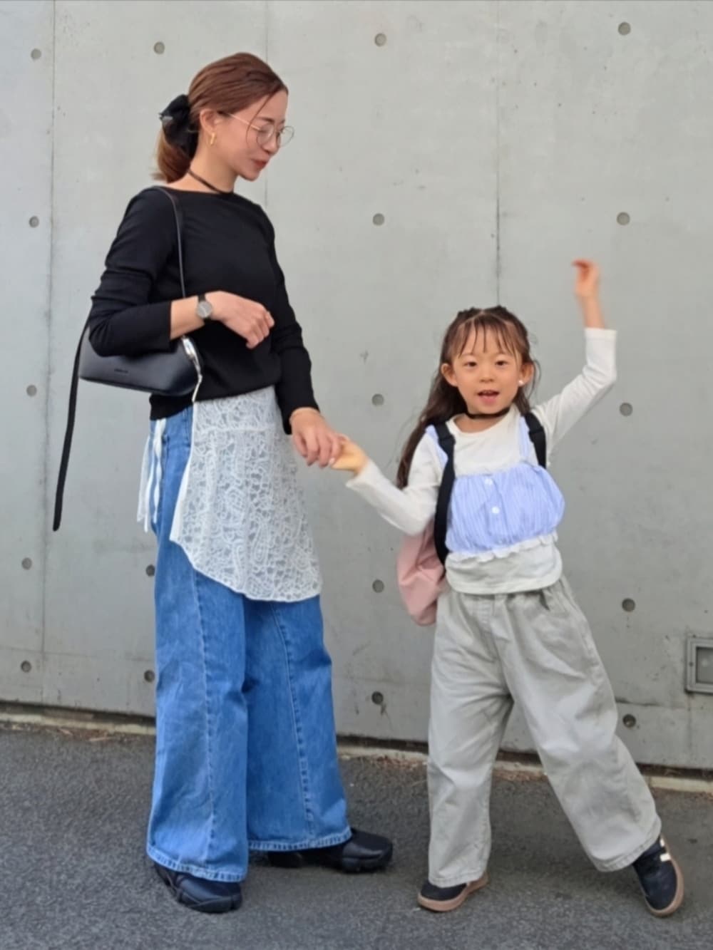 ブラック系のスニーカー、ブルー系のデニムパンツを着用したレディースの春コーディネートの2枚目の写真