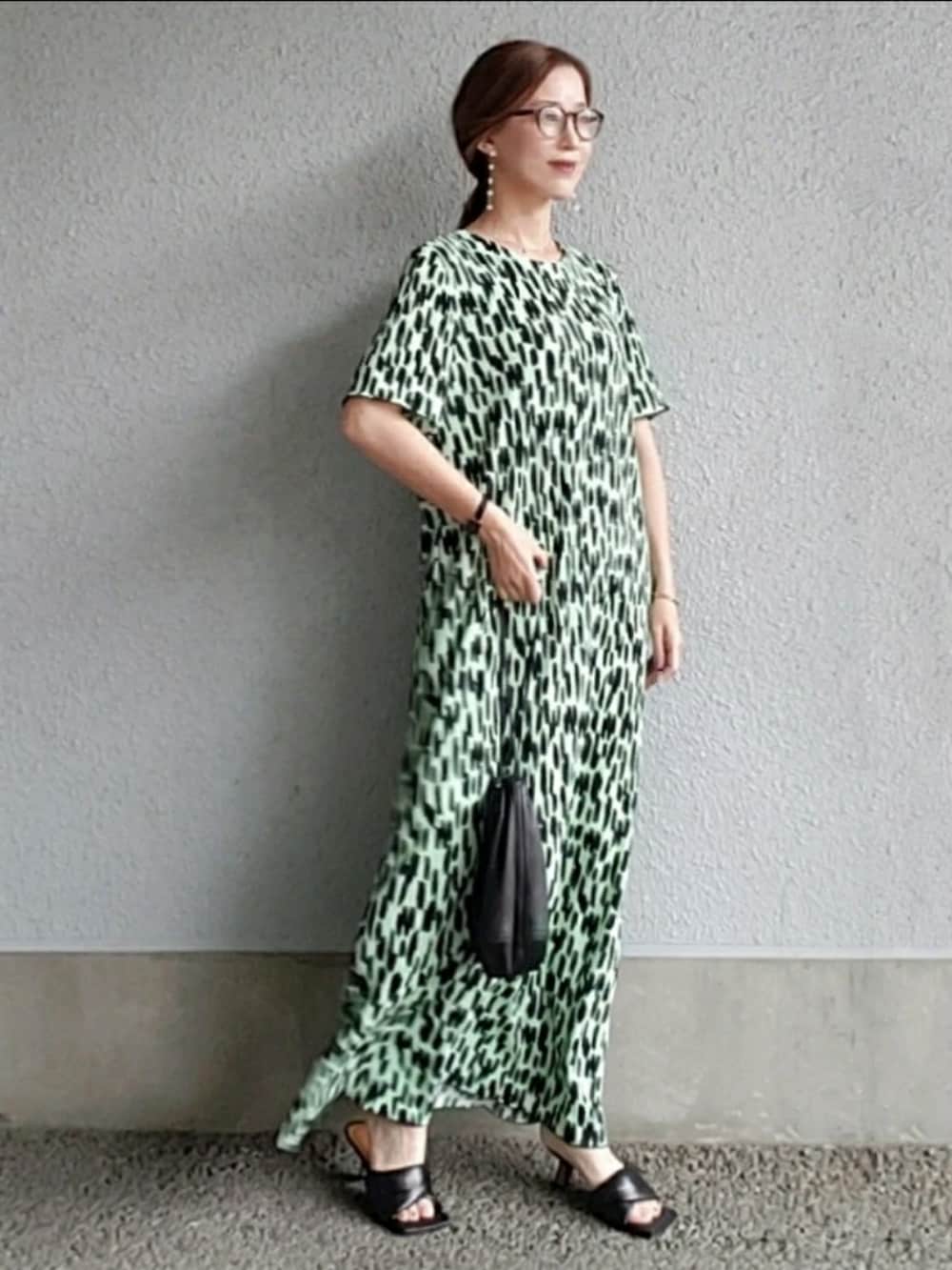 グリーン系のワンピース、ブラック系のバッグ、ブラック系のサンダルを着用したレディースの春コーディネートの3枚目の写真