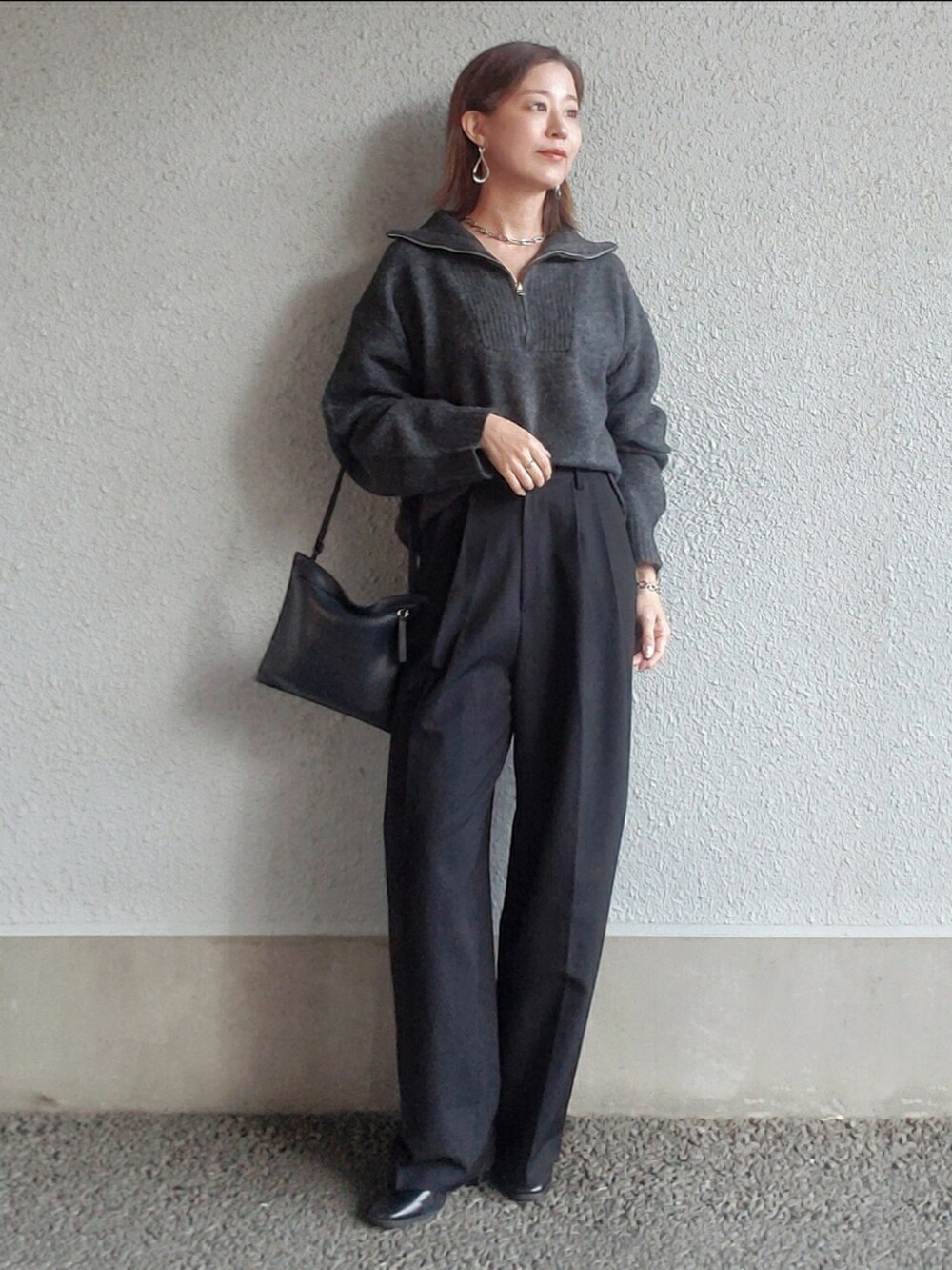 ブラック系のスラックス、ブラック系のブーツ、シルバー系のピアス（両耳用）を着用したレディースの冬コーディネートの3枚目の写真