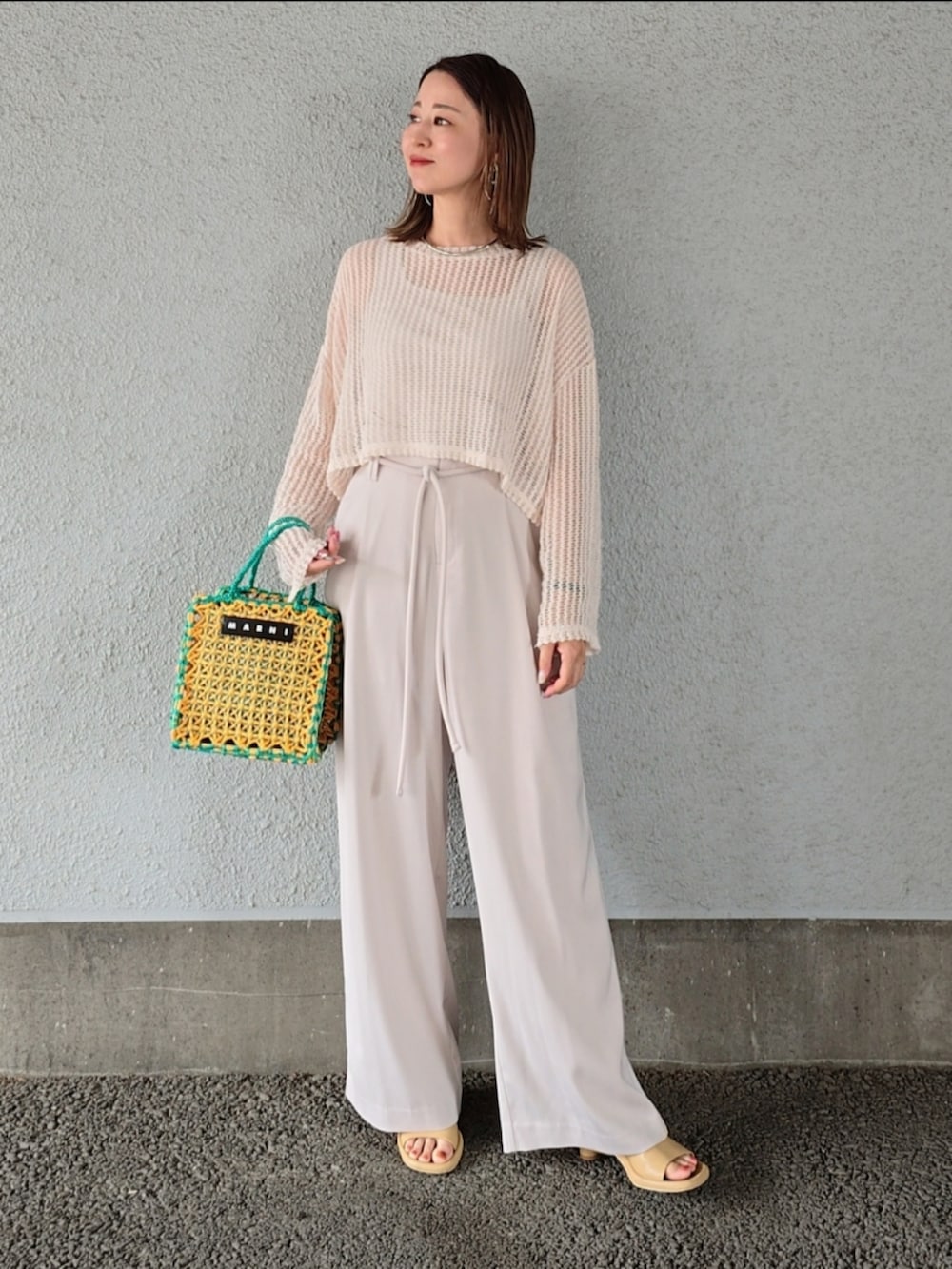イエロー系のバッグ、ホワイト系のその他パンツ、ベージュ系のニット/セーターを着用したレディースの春コーディネートの3枚目の写真