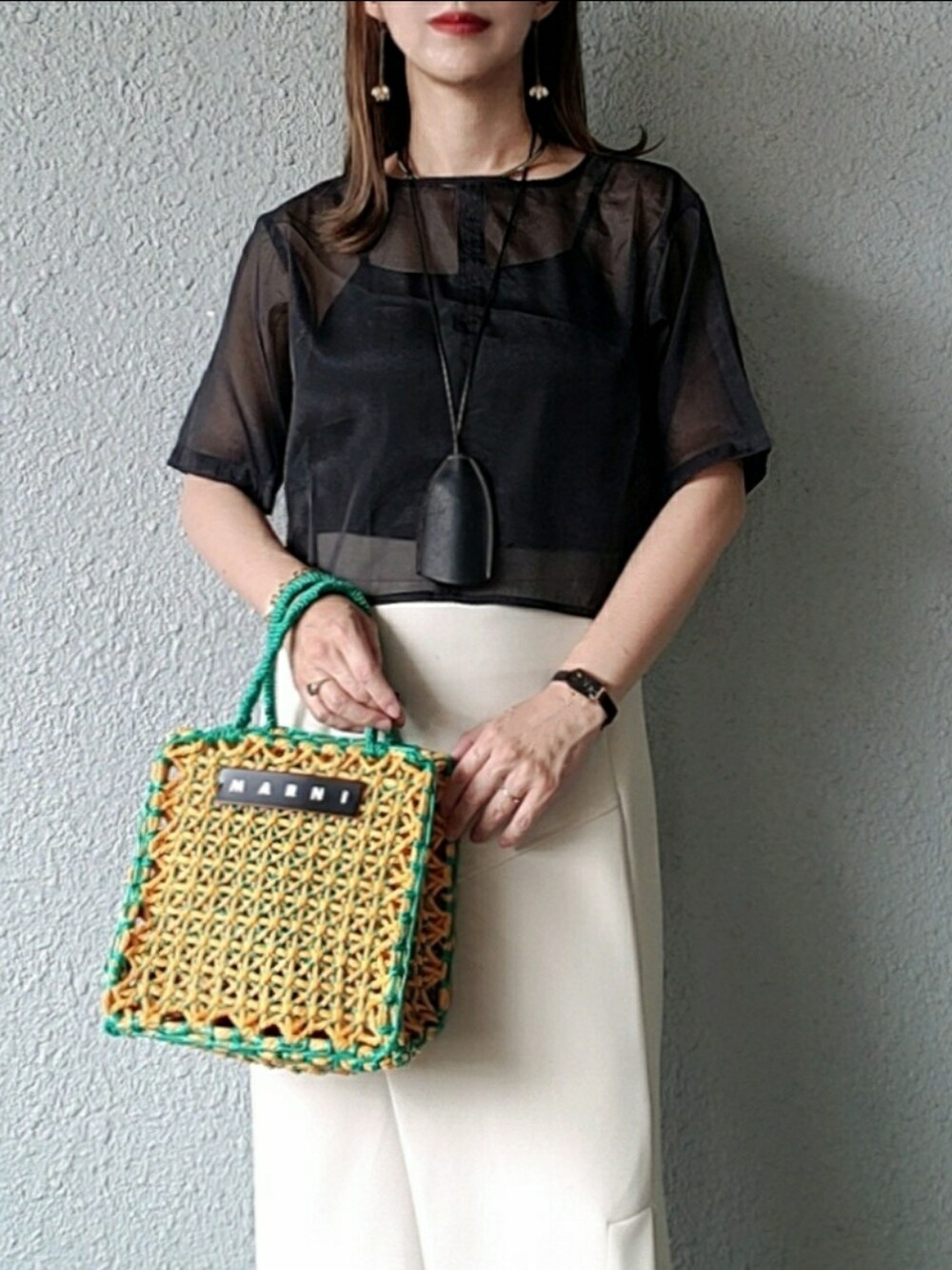 ブラック系のトップス、ベージュ系のスカート、グレー系のサンダルを着用したレディースの夏コーディネートの2枚目の写真