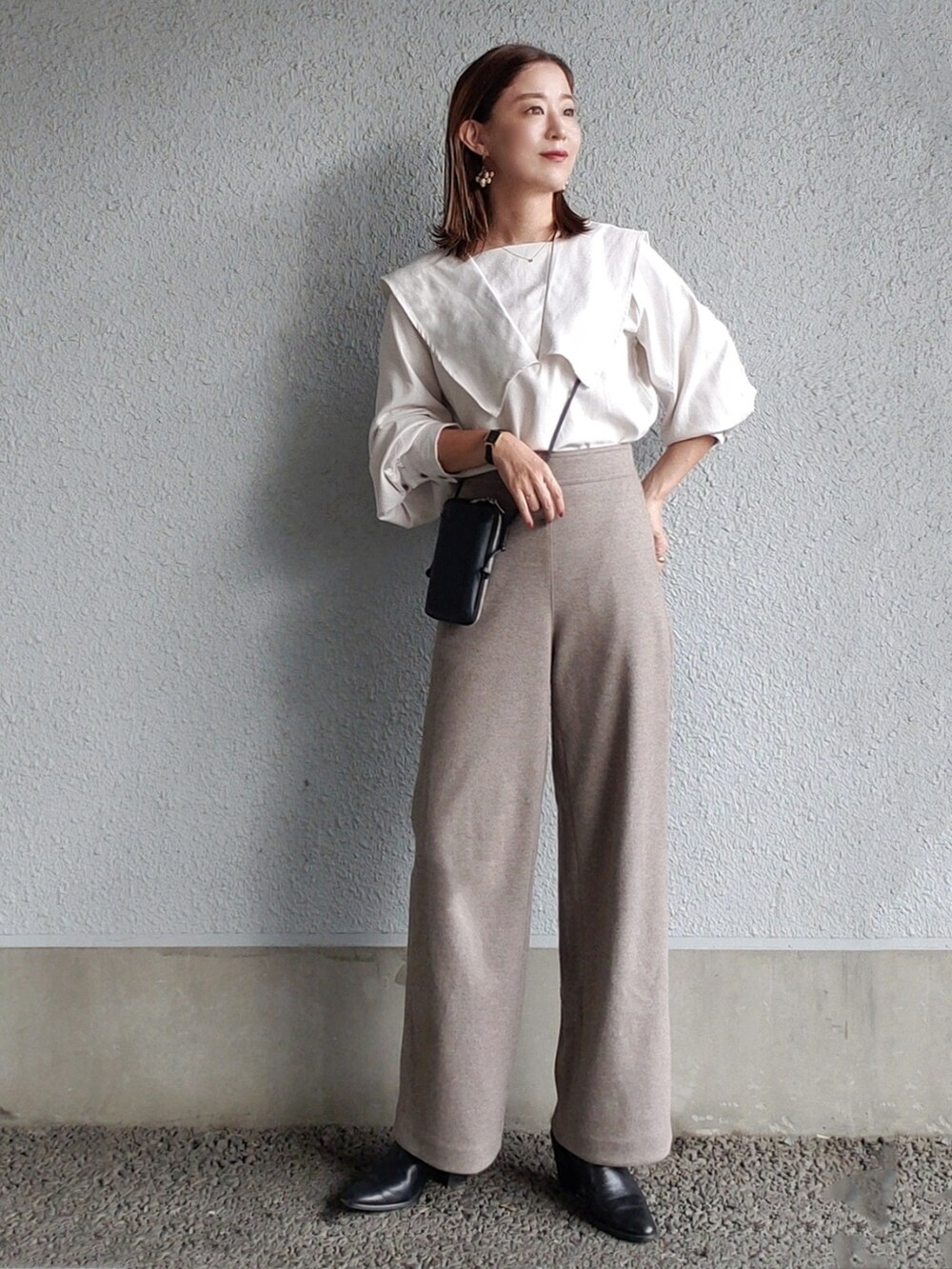 ホワイト系のシャツ/ブラウス、ベージュ系のパンツ、ブラック系のブーツを着用したレディースの秋コーディネートの2枚目の写真