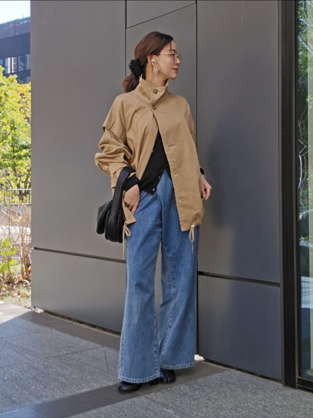 ベージュ系のトレンチコート、ブラック系のトップス、ブルー系のデニムパンツを着用したレディースの冬コーディネートの2枚目の写真