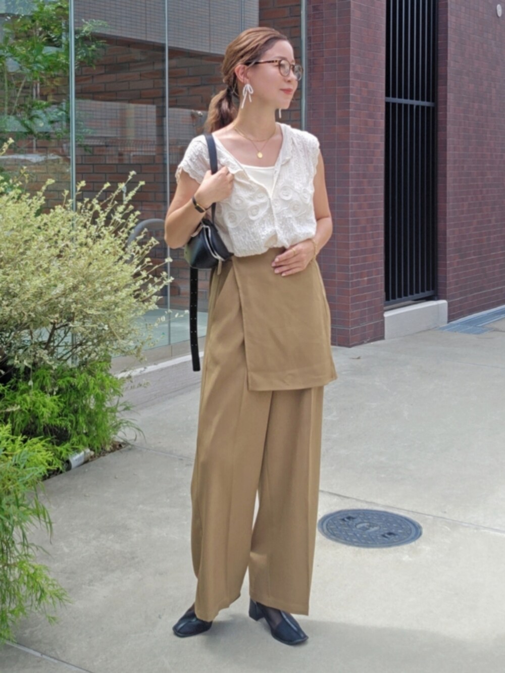 ホワイト系のシャツ/ブラウス、ベージュ系のスラックス、ブラック系のブーツを着用したレディースの夏コーディネートの2枚目の写真