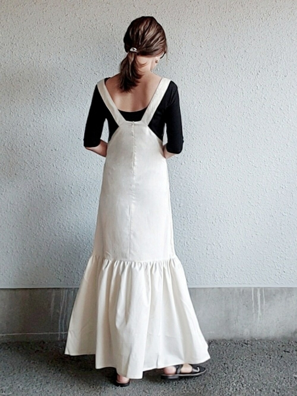 ホワイト系のジャンパースカート、ブラック系のTシャツ/カットソー、ブラック系のサンダルを着用したレディースの春コーディネートの2枚目の写真