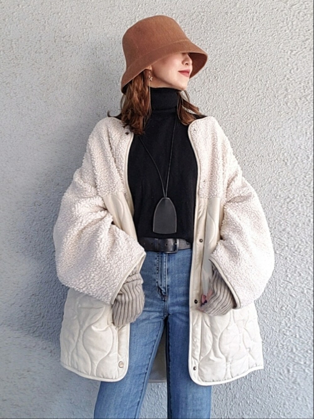 ブルー系のパンツ、ブラック系のニット/セーター、ベージュ系のブーツを着用したレディースの冬コーディネートの2枚目の写真