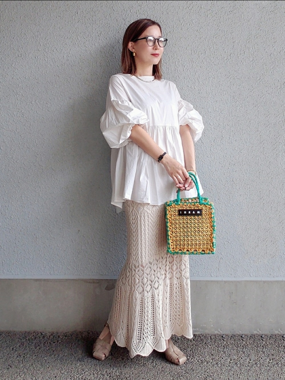 イエロー系のバッグ、ホワイト系のスカート、グレー系のサンダルを着用したレディースの春コーディネートの3枚目の写真