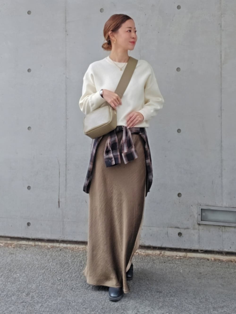 グリーン系のスカート、ベージュ系のバッグを着用したレディースの冬コーディネートの2枚目の写真