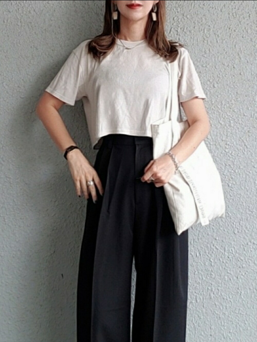 ブラック系のスラックス、グレー系のTシャツ/カットソー、ホワイト系のトートバッグを着用したレディースの夏コーディネートの3枚目の写真