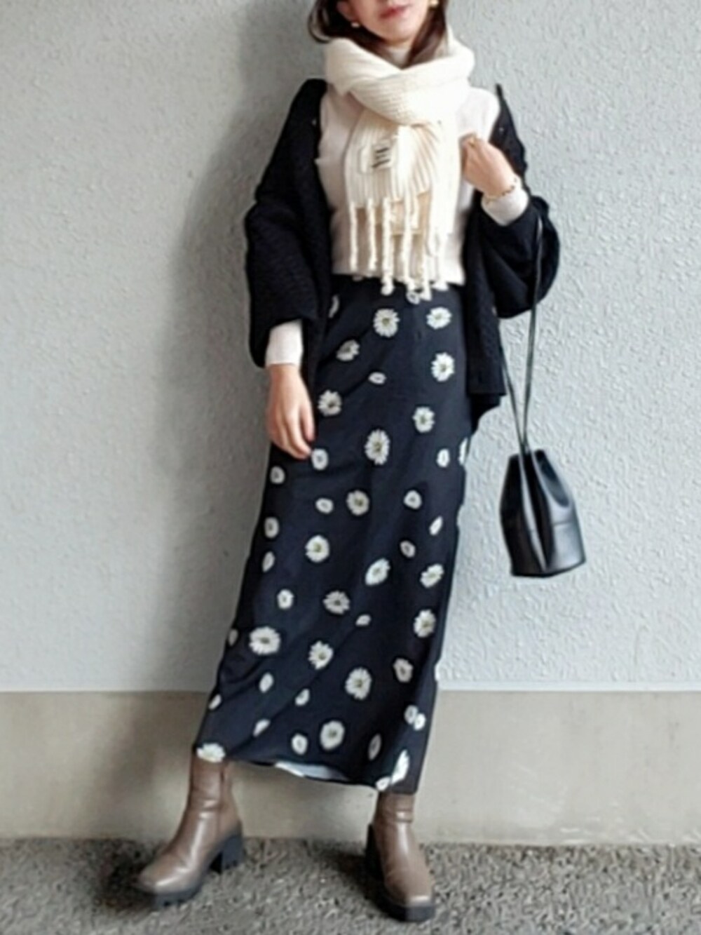 ブラック系のスカート、ベージュ系のブーツ、ブラック系のハンドバッグを着用したレディースの冬コーディネートの2枚目の写真