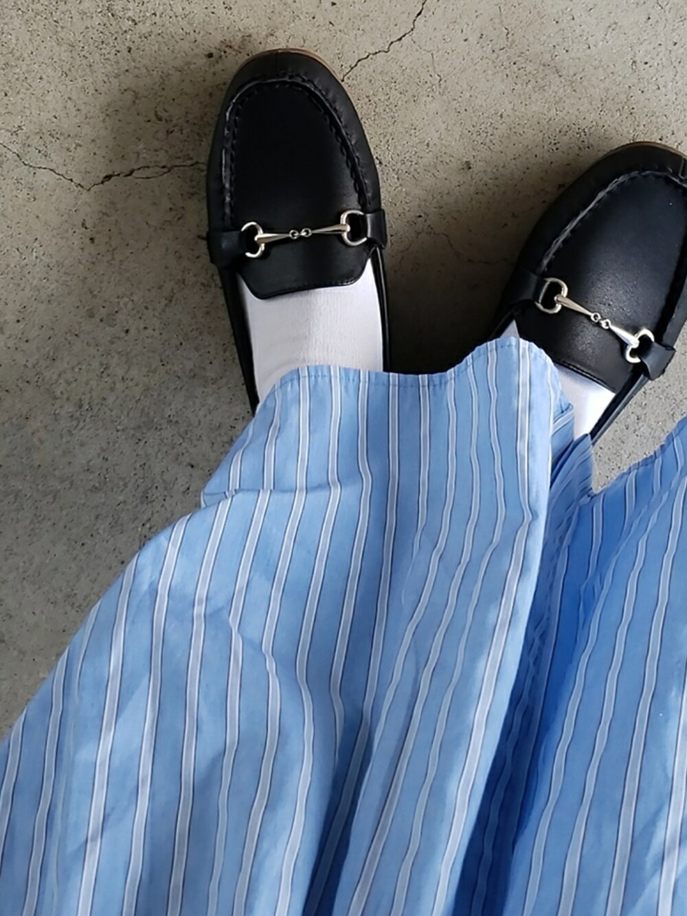 ブラック系のベスト、ブルー系のシャツワンピース、ブラック系のローファーを着用したレディースの春コーディネートの4枚目の写真