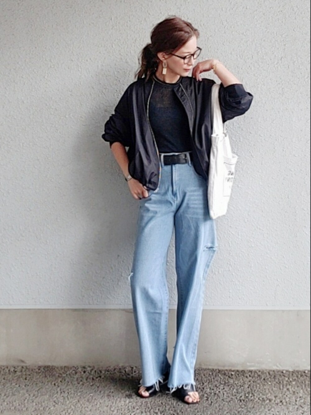 グレー系のニット/セーター、ブルー系のデニムパンツ、ブラック系のサンダルを着用したレディースの春コーディネートの2枚目の写真