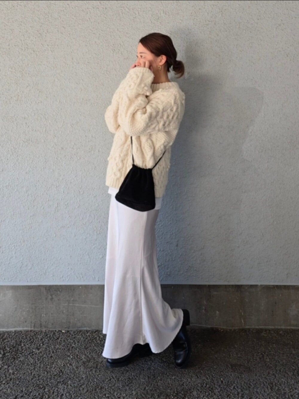 ブラック系のバッグ、ホワイト系のスカート、ホワイト系のニット/セーターを着用したレディースの冬コーディネートの3枚目の写真