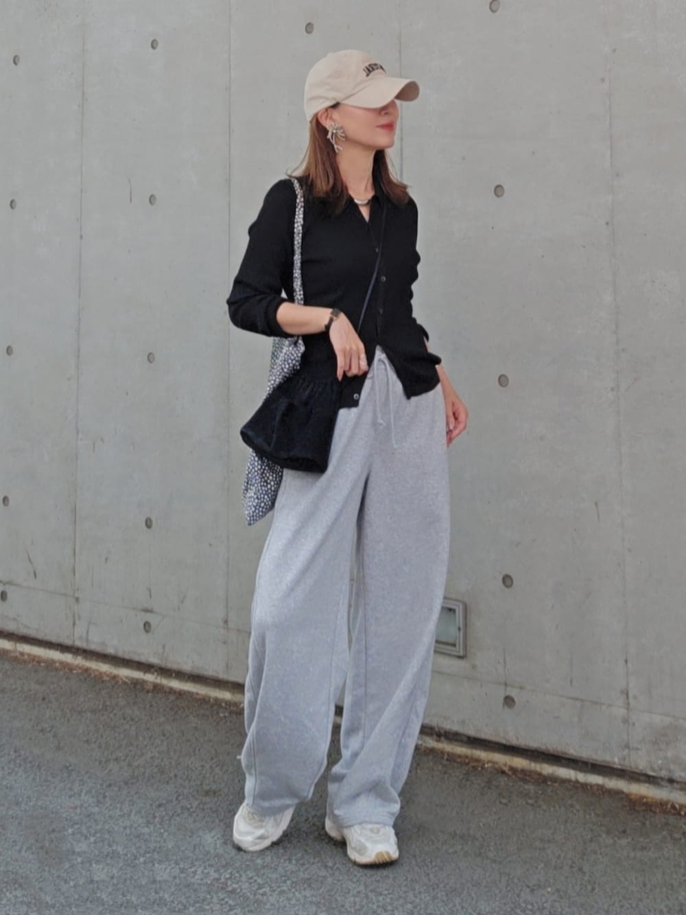 グレー系のパンツ、ベージュ系のスニーカー、ブラック系のトップスを着用したレディースの春コーディネートの2枚目の写真