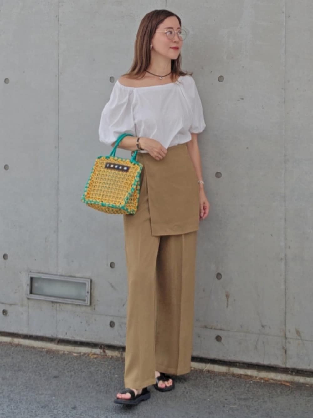 ベージュ系のその他パンツ、イエロー系のバッグ、ブラック系のサンダルを着用したレディースの夏コーディネートの2枚目の写真