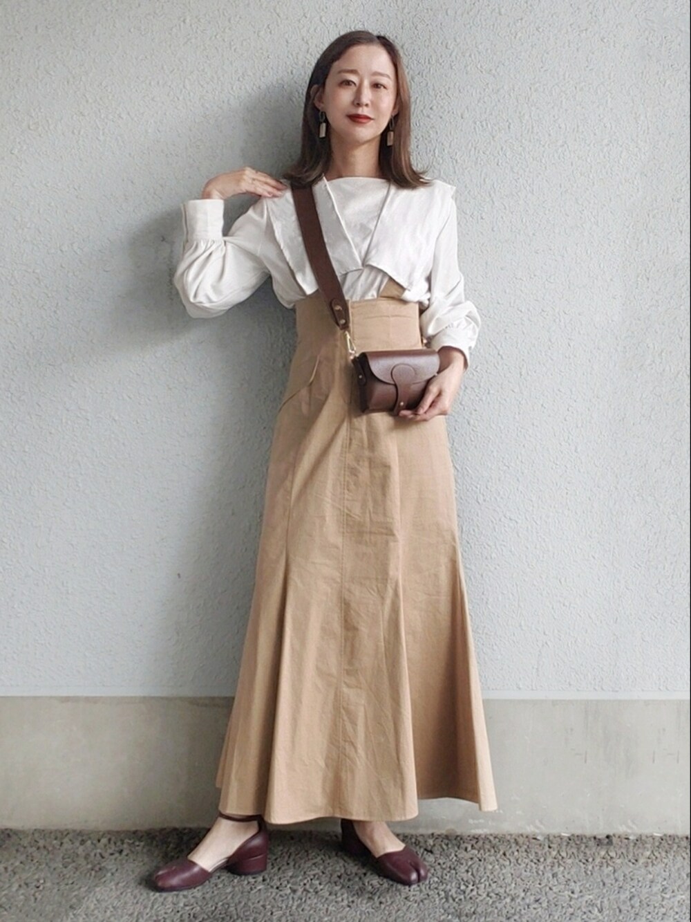 ベージュ系のスカート、ブラウン系のシューズ、ブラウン系のショルダーバッグを着用したレディースの春コーディネートの2枚目の写真