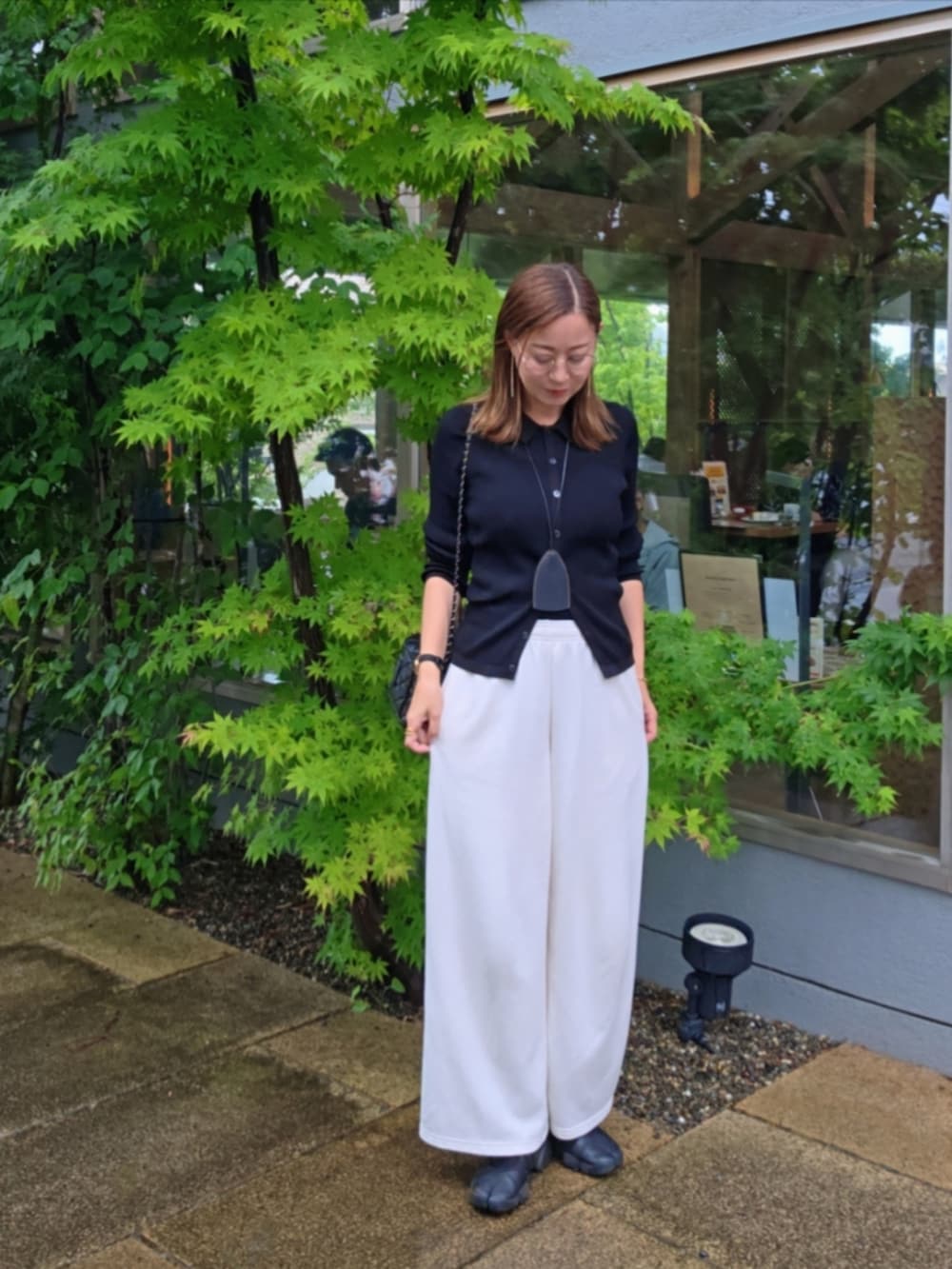 ホワイト系のパンツ、ブラック系のスニーカーを着用したレディースの夏コーディネートの2枚目の写真