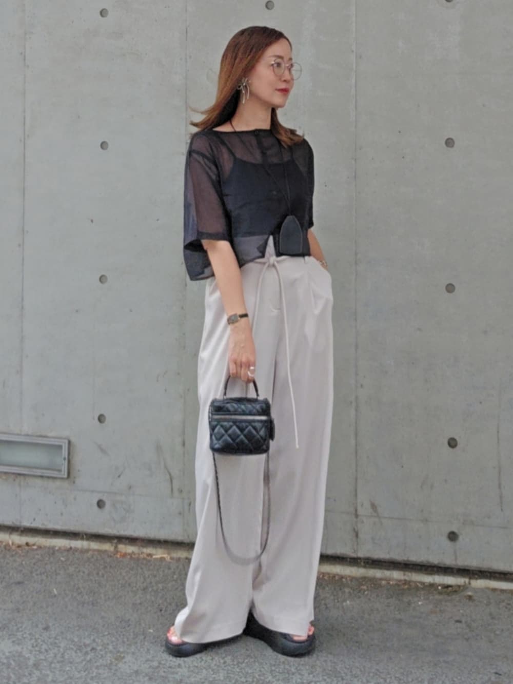 ブラック系のトップス、ブラック系のシューズ、ブラック系のスラックスを着用したレディースの夏コーディネートの2枚目の写真