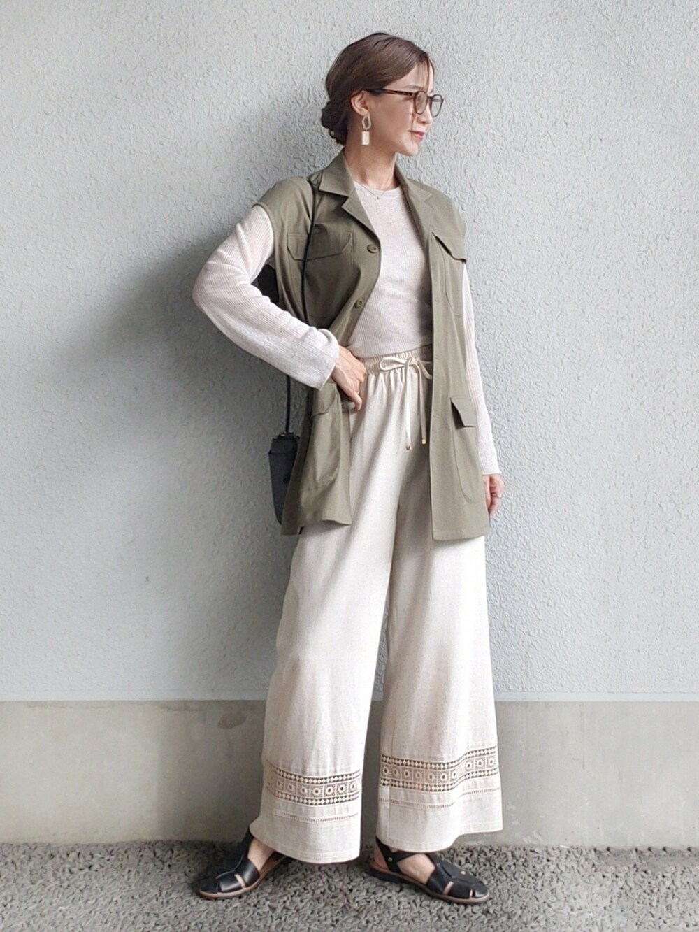 グリーン系のベスト、ベージュ系のその他パンツ、ブラック系のサンダルを着用したレディースの春コーディネートの2枚目の写真