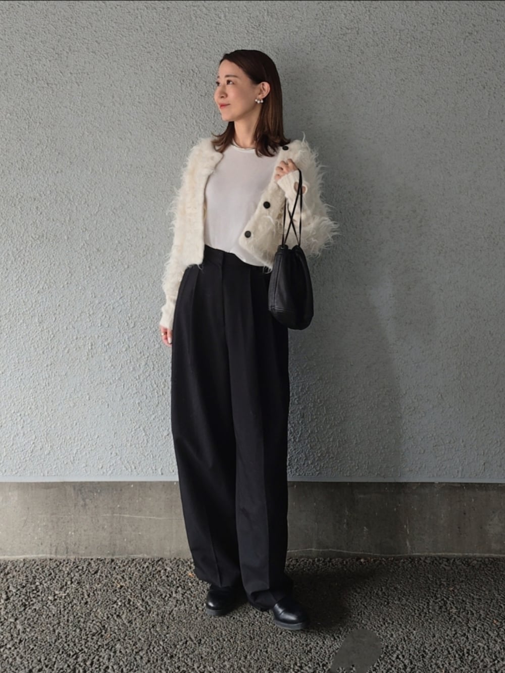 ブラック系のスラックス、ブラック系のパンプス、ブラック系のバッグを着用したレディースの冬コーディネートの2枚目の写真