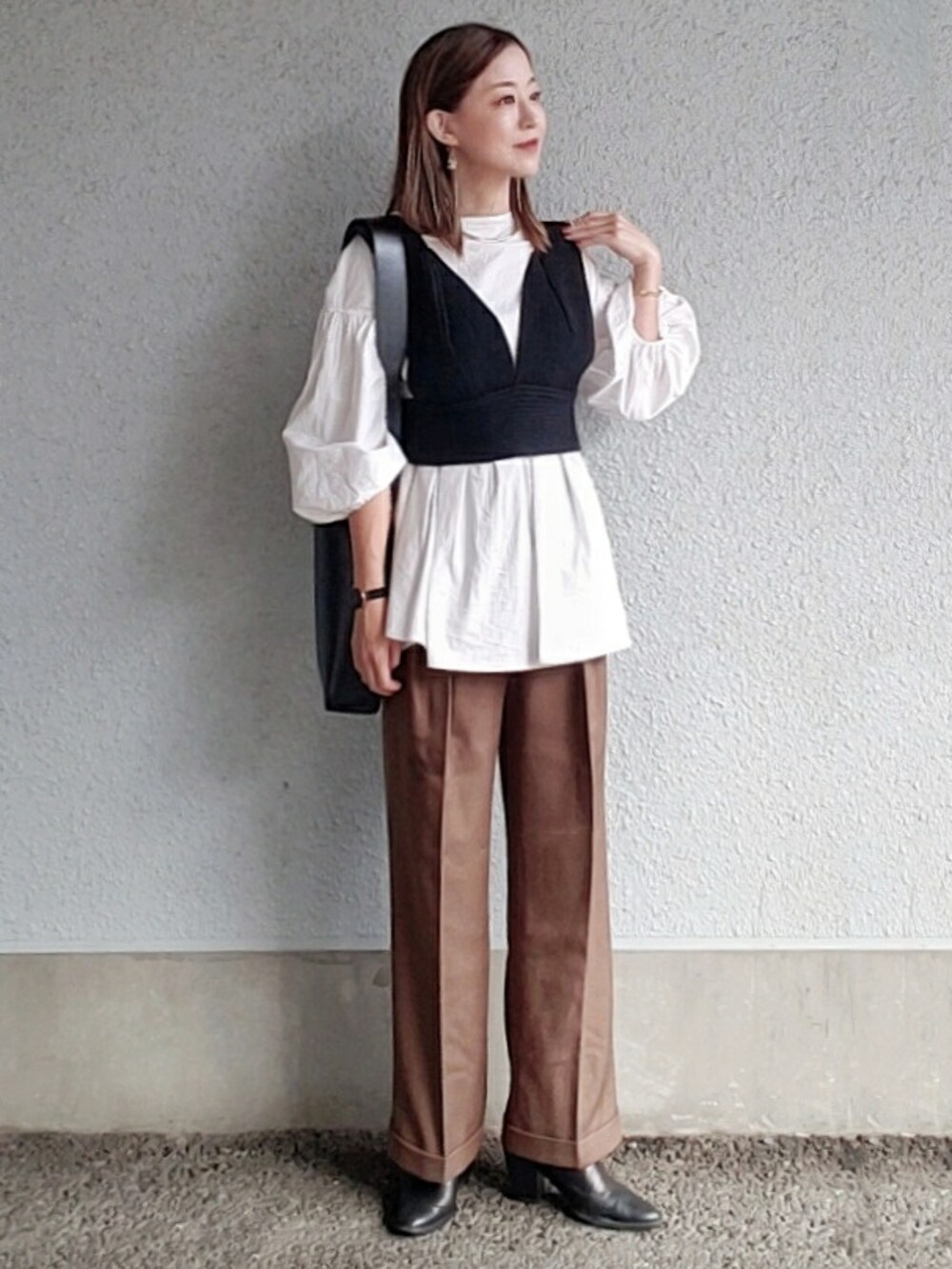 ブラウン系のパンツ、ブラック系のベスト、ホワイト系のシャツ/ブラウスを着用したレディースの冬コーディネートの3枚目の写真