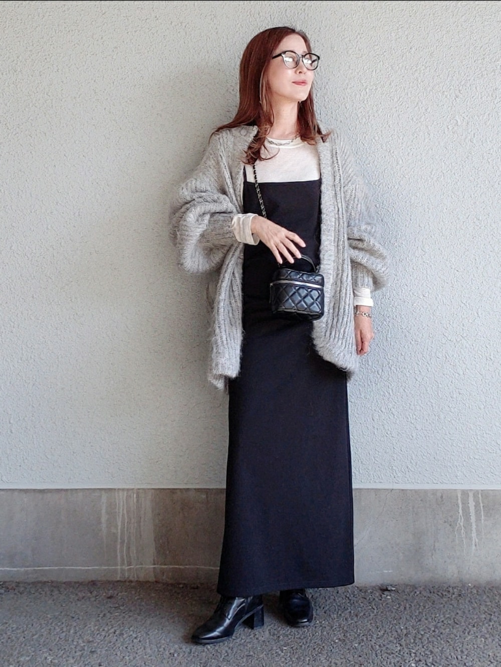 グレー系のカーディガン/ボレロ、ブラック系のワンピース、ブラック系のブーツを着用したレディースの秋コーディネートの2枚目の写真